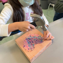 -primary students nailed heart-shaped outlines onto wood and wove yarn to fill the center for February, friendship and family month (grades K to 2)